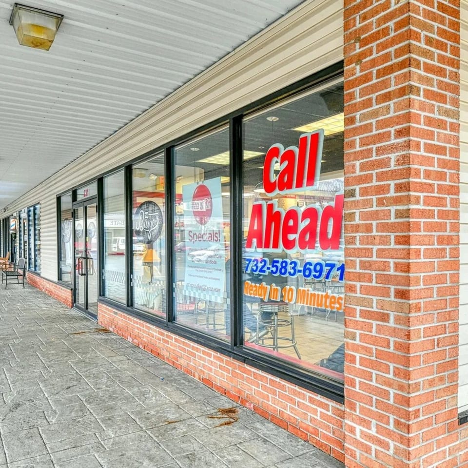 Exterior of The Burger Shop with a "Call Ahead" sign and specials visible through the window.