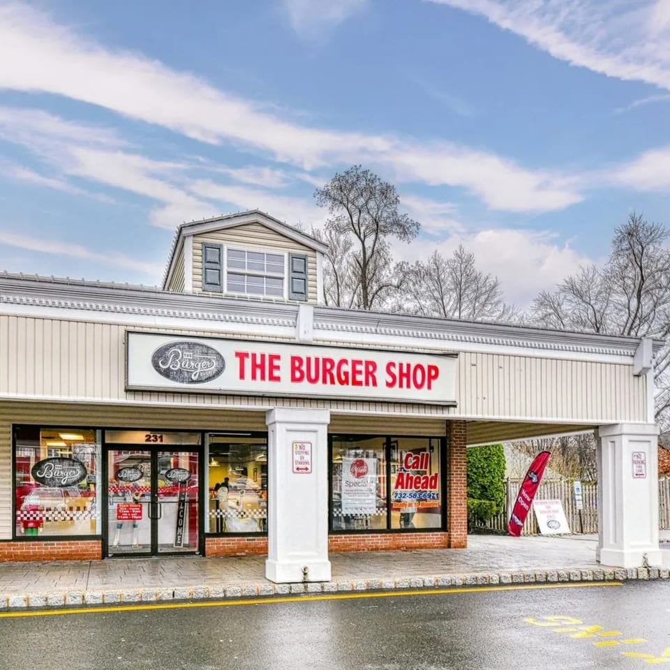 The Burger Shop's exterior features a beige facade, large windows, and a red and white sign.