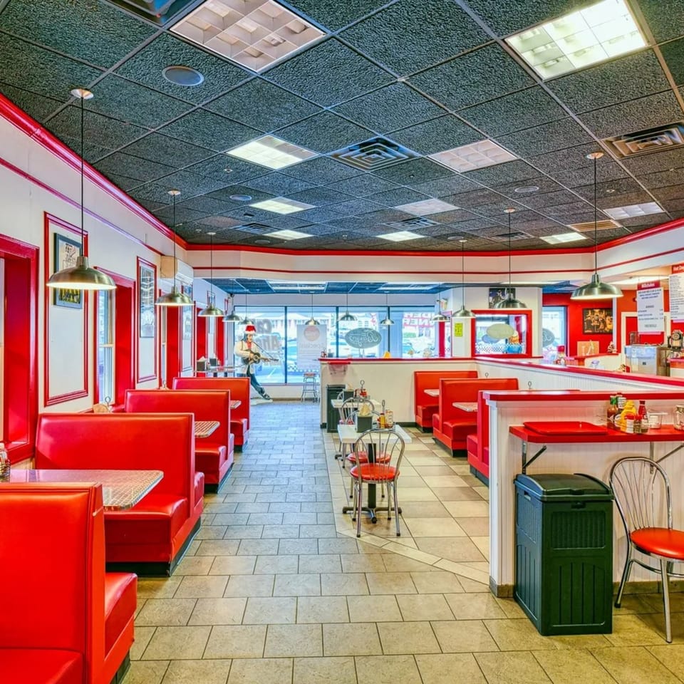 Interior of The Burger Shop with red booths, white tables, and a mannequin playing guitar.
