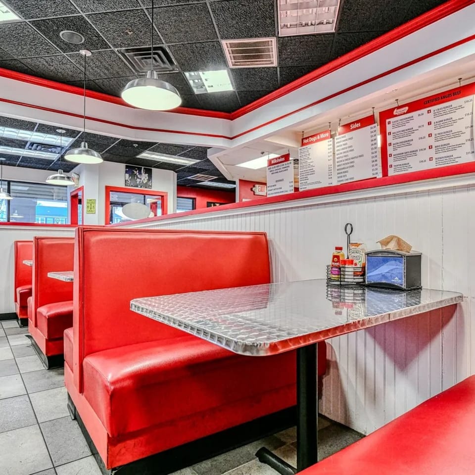 Interior of The Burger Shop with red booths, diamond plate tables, and menu boards on the wall.