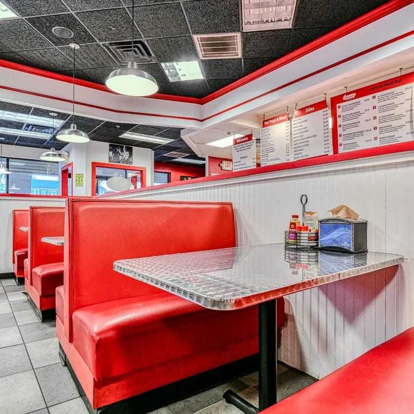 Interior of The Burger Shop with red booths, diamond plate tables, and menu boards on the wall.
