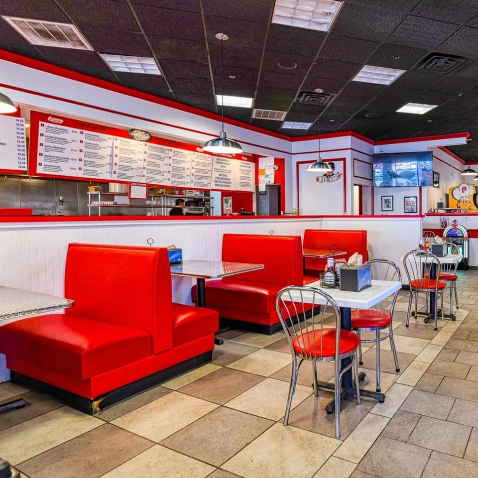 Interior of The Burger Shop with red booths, white tables, and a menu board.