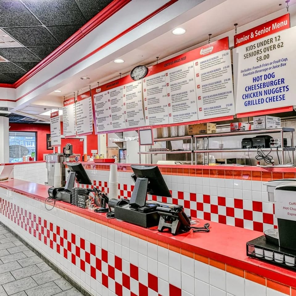 The Burger Shop's counter with red and white checkered tiles, menus, and ordering stations.